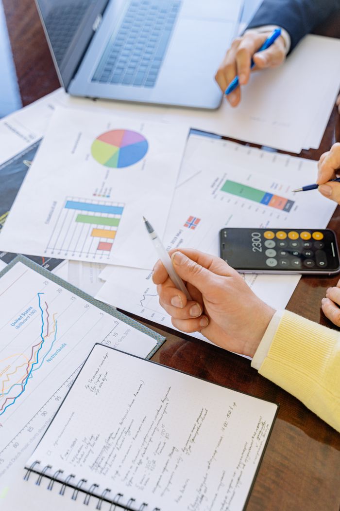 services-01 A close-up of businesspeople analyzing financial data and charts during a meeting.