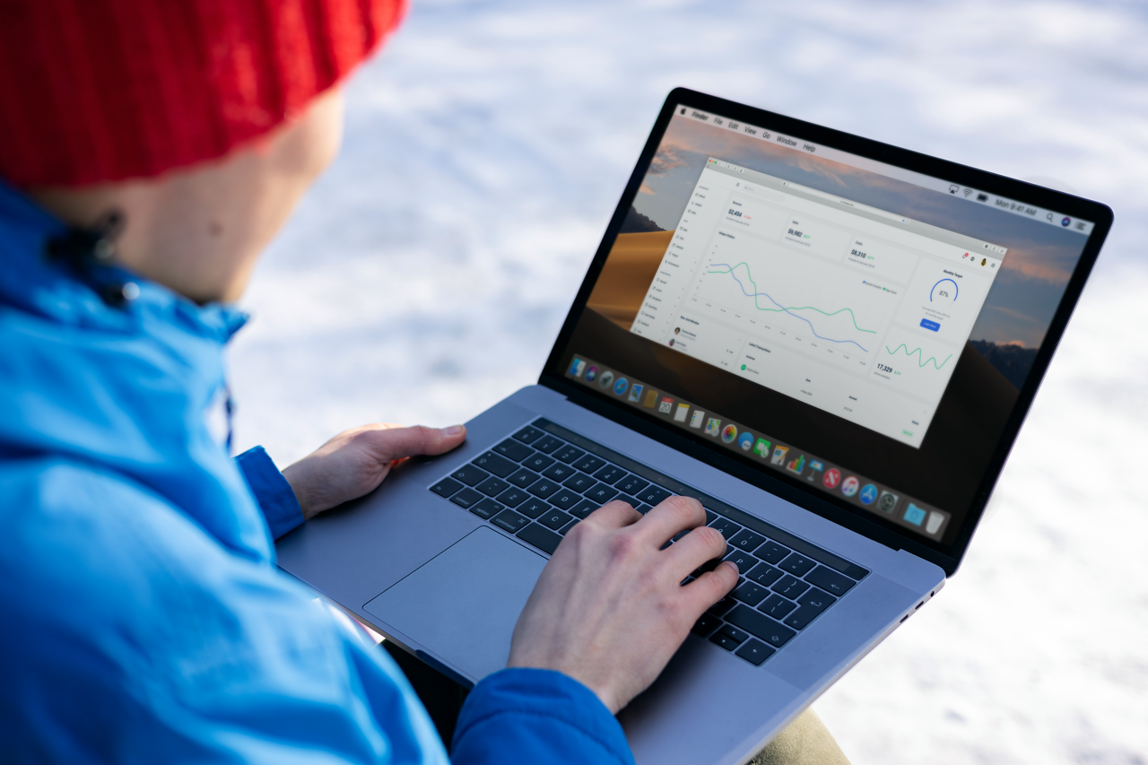 about-us-02 Person working on a laptop analyzing charts in an outdoor setting during winter.